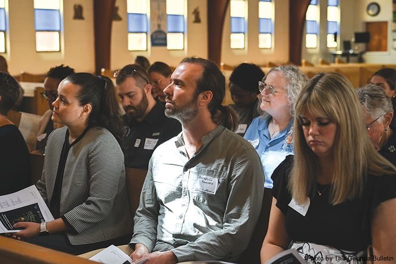 Harrison Hanvey, center, manager of outreach and partnerships at the Jesuit Conference Office of Justice and Ecology, sits in prayer during the service at Our Lady of Lourdes Church to kick off the National Catholic Conference on Restorative Justice. Photo by Julianna Leopold 