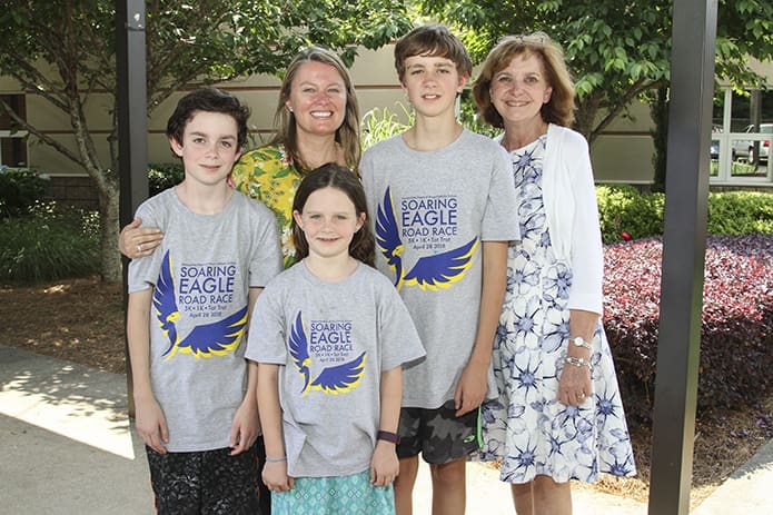 Diana (Barnsley) Fleming, background, second from left, graduated from Immaculate Heart of Mary School in 1989 when Sandy Wilson, far right, was the librarian. Over the last several years, Fleming’s own children, (l-r) Charlie (sixth grade), Coco (third grade) and Jake (eighth grade) have been exposed to the librarian that has touched so many children for nearly four decades. Photo By Michael Alexander