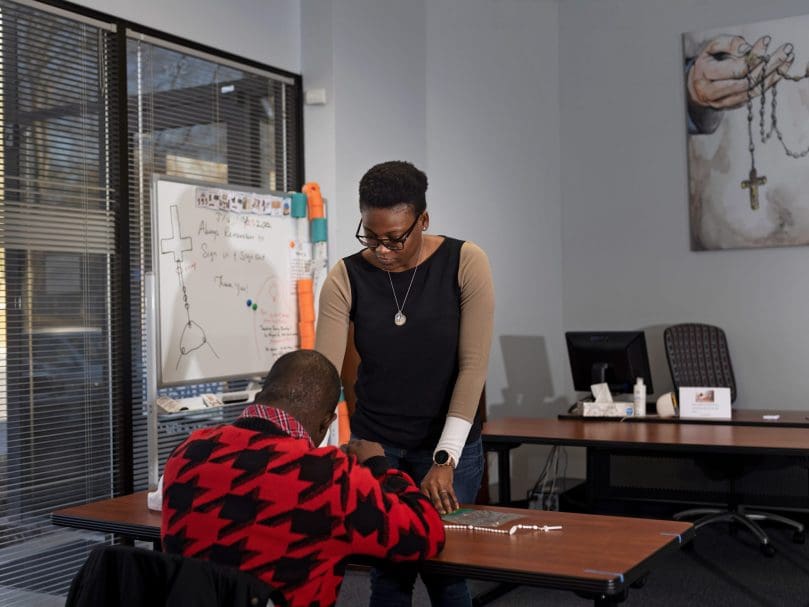 Adminstrator Cynthia Okoro assists Ikenna Ihenacho at the Rosary Makers of America office. Photo by Johnathon Kelso