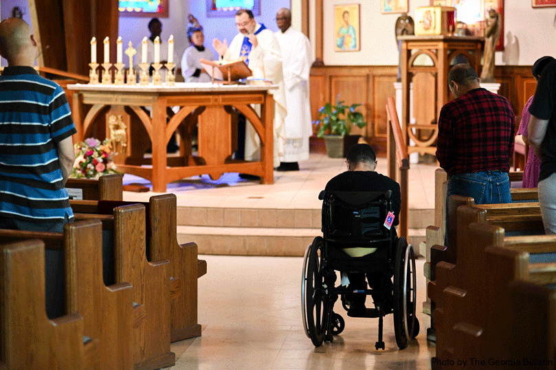Leo Milano sits in his wheelchair in the aisle during the sensory Mass at St. John Vianney Church in Lithia Springs. It is his first time back to Mass in years. The shorter Mass featured dimmed lighting, soft music and no bells. Photo by Julianna Leopold