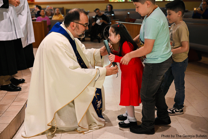 Senia Isabella Calderon, middle, brings up the gifts to Father Jack Knight, pastor of St. John Vianney Church, left, with the support of her brothers, José Daniel Calderon and Alex Caleb Calderon. The sensory Mass is designed for parishioners with autism, Down syndrome, intellectual disabilities, the elderly or anyone with sensory sensitivities. Photo by Julianna Leopold