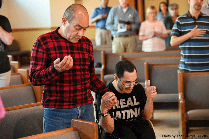 Leo Milano, right, and his father, Jose Milano, left, hold hands during the Our Father at St. John Vianney's first sensory Mass designed especially for parishioners with autism, Down syndrome, intellectual or physical disabilities and others with sensory sensitivities. Photo by Julianna Leopold