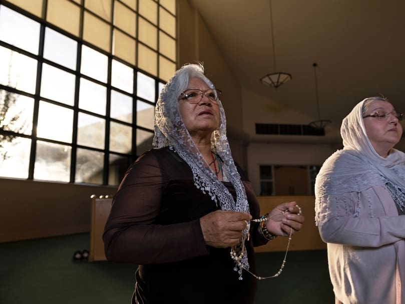 Fermina Consla, center, and Olga Jennings, right, of the Seven Sisters Apostolate pray for their parochial vicar in the sanctuary at St. Pius X Church. The parish's other group, the first to form there, prays solely for the pastor. Photo by Johnathon Kelso
