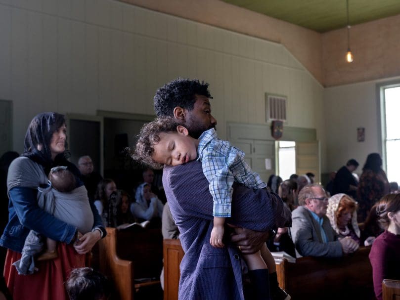 Parishoner Ahmaud Templeton holds his son during the sung Sunday Mass at St. Aelred Church. Photo by Johnathon Kelso