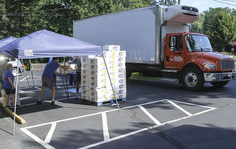 St. Vincent de Paul Society volunteers from St. Ann Church, Marietta, remove boxes of produce from a pallet. It was part of the 4,381 pounds of produce, in addition to butter, cheese, diced chicken and milk delivered to the parish July 13. Photo By Michael Alexander