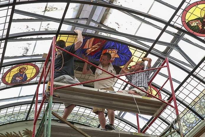 (L-r) Frank Llorens Jr., Robert Zortea and Frank Sr. install the second of four 30-by-71.5 inch panels that comprise the new major icon in the refurbished vaulted glass skylight. Photo By Michael Alexander