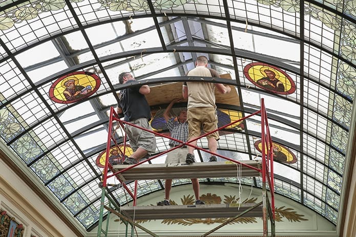 (L-r) Frank Llorens Jr., Frank Sr. and Robert Zortea install the third of four 30-by-71.5 inch panels that comprise the new major icon in the refurbished vaulted glass skylight. Photo By Michael Alexander