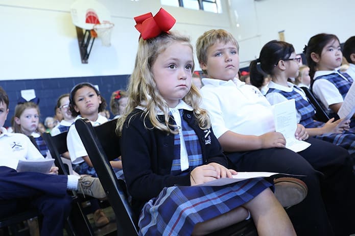 Second-graders Clara York, left center, and Wyatt Wood, right center, draw their attention to the student doing the first reading from the Book of Thessalonians. Photo By Michael Alexander