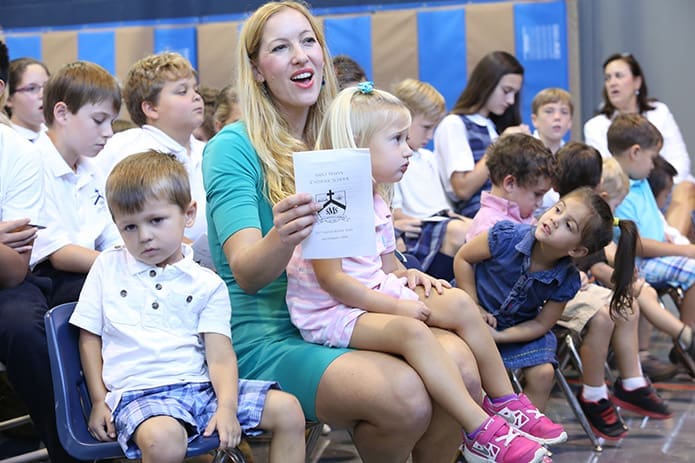 Pre-kindergarten instructor Josclyn Giles sits among her students as she sings the Communion hymn with the student choir. Photo By Michael Alexander