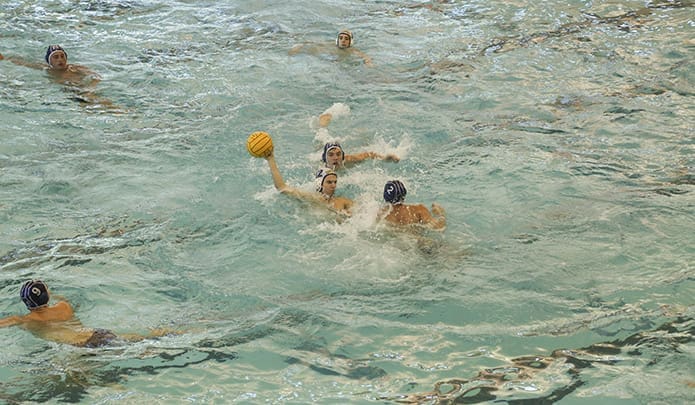 St. Pius X senior Robert Benoit (#12) fires off a successful shot between two Blue Devil players in the Oct. 9 semifinal match. Assistant coach Father Dan Rogaczewski said Benoit is undersized for his position as center forward, but he makes up for it with great hustle and anticipation. Photo By Michael Alexander