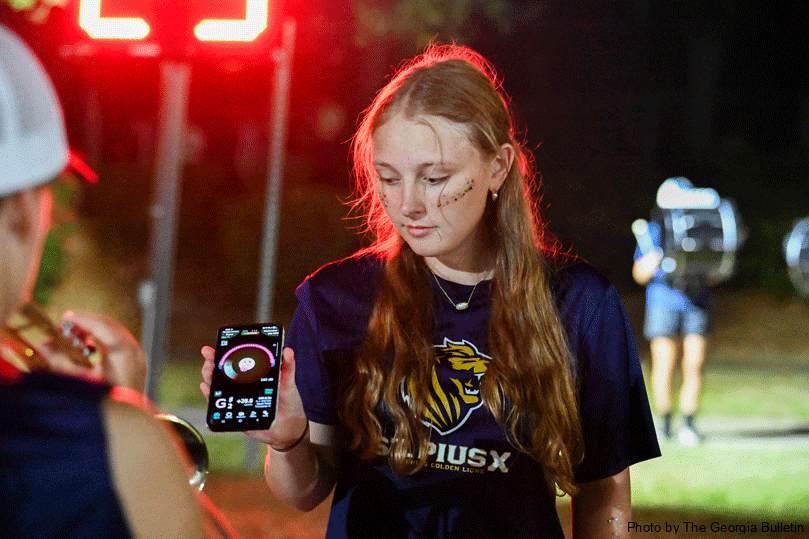 Zoe Leiner, senior drum major, prepares before the halftime show by helping her band members tune their instruments using an app. Photo by Julianna Leopold 
