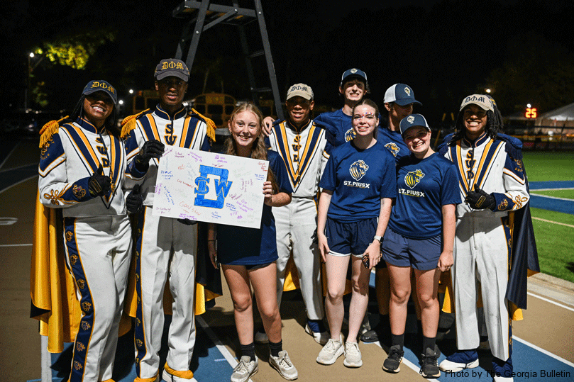 Members of the Marching Golden Lions hand off a hand-made poster to band of the competing team, Southwest Dekalb High School, on Sept. 19. The bands watched each other perform during the halftime show. The poster gift is a tradition for every home football game.  Photo by Julianna Leopold