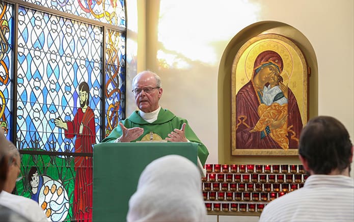 Jesuit Father Pat Earl, parochial vicar, presents his homily during the 5:30 p.m. weekday Mass in the parish chapel. Father Earl told the congregation that in our love for others God is present; therefore, we should grow that love and spread it. Photo By Michael Alexander