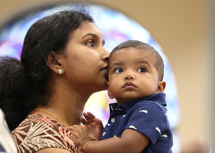 Shinu Mattappally, who likes to attend the weekday evening Mass in the parish chapel at St. Thomas More Church, Decatur, holds her 14-month-old son Noah in her arms. Photo By Michael Alexander