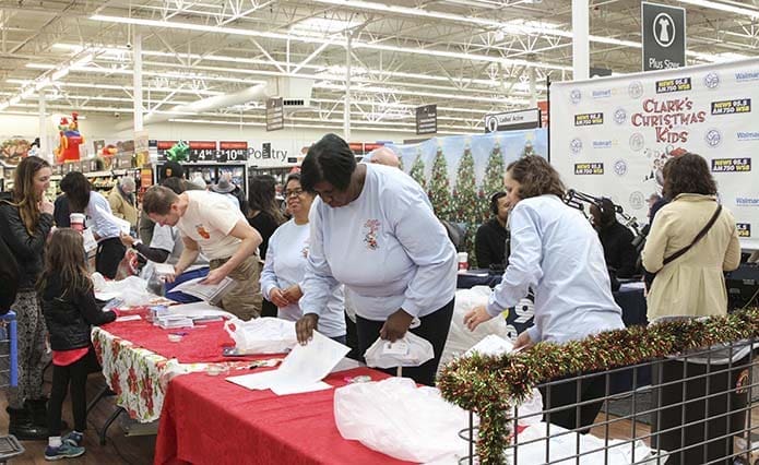 St. Vincent de Paul Georgia volunteers, dressed in light blue sweatshirts, provide help to those donating toys during the 27th annual Clark’s Christmas Kids gift drive for foster children at the Walmart store on Cobb Parkway in Marietta. Photo By Michael Alexander