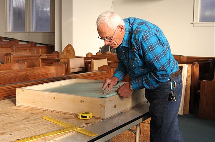 St. Joseph Church parishioner Bernard Wysocki cuts the extruded polystyrene insulation that serves as a protective barrier inside the wooden crates that hold the stained glass window panels. Photo By Michael Alexander
