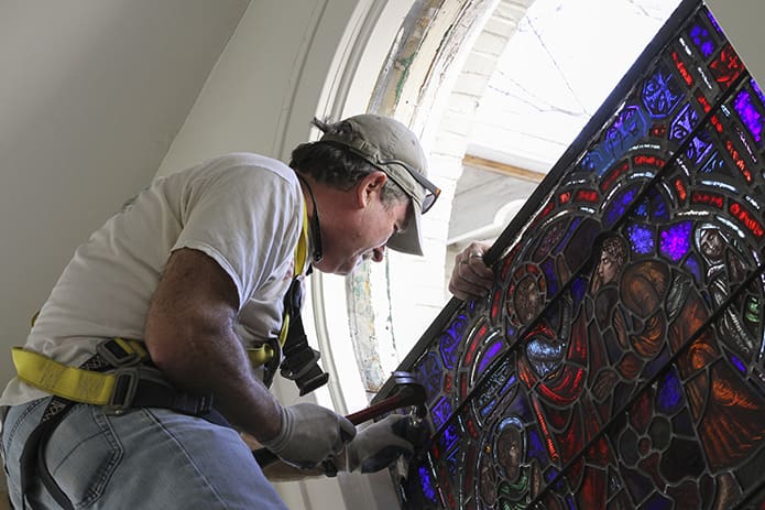 Wooten removes another section of stained glass from one of the last three large windows remaining in the church. Photo By Michael Alexander