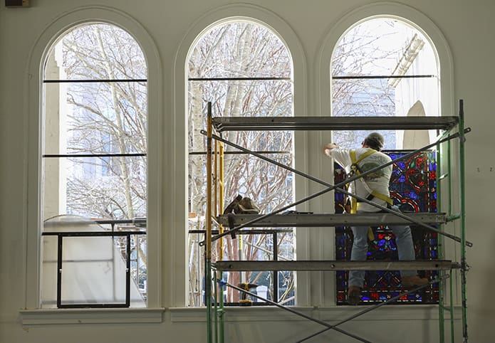 On a balmy Jan. 13 morning Avery Wooten, the owner of Foothill Sand To Glass of Union Grove, N.C., works from a scaffold as he removes one of the final stained glass window panels from St. Joseph Church, Athens. This particular window was a depiction of Jesus walking on water. Photo By Michael Alexander