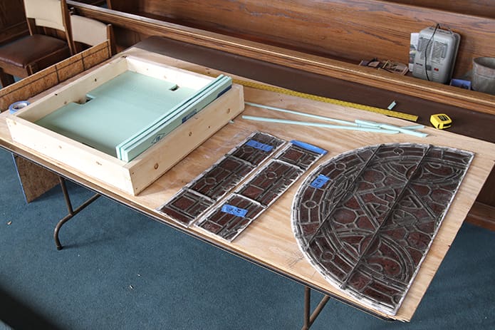 Stained glass window panels rest on a table before they are packed in the protected crate. Photo By Michael Alexander