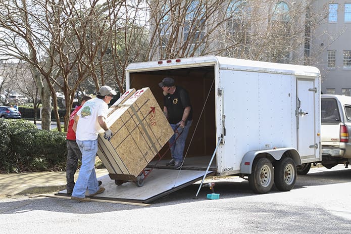 (Clockwise, from top right) Foothill Sand To Glass employees Michael Farmer, Avery Wooten and David Mitchell load the wooden crates, packed with labeled stained glass window panels, onto a trailer where they were later taken to be stored. Photo By Michael Alexander