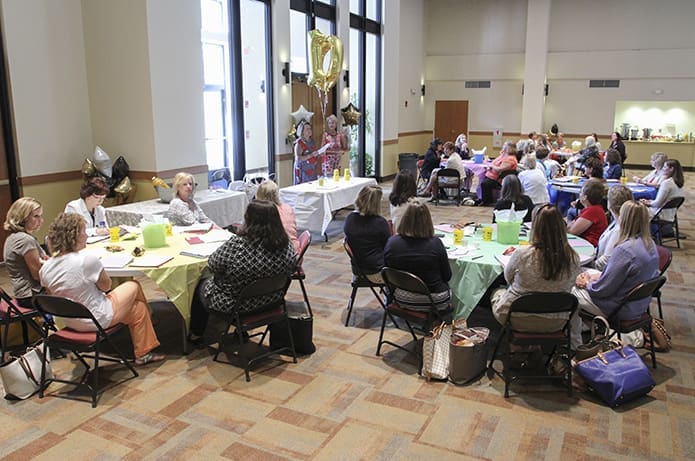 As 10th anniversary Summer Education Institute balloons loom overhead, (background, l-r) Ceci McAuliffe, left, presenter and Terry Graham, archdiocesan director of parish preschools, take care of some housekeeping items just prior to the workshop for preschool directors. Photo By Michael Alexander