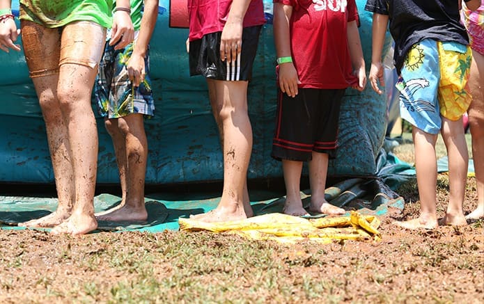Kids with muddy feet, wet legs and soaked apparel wait for another turn to go down the Big Kahuna water slide. Photo By Michael Alexander