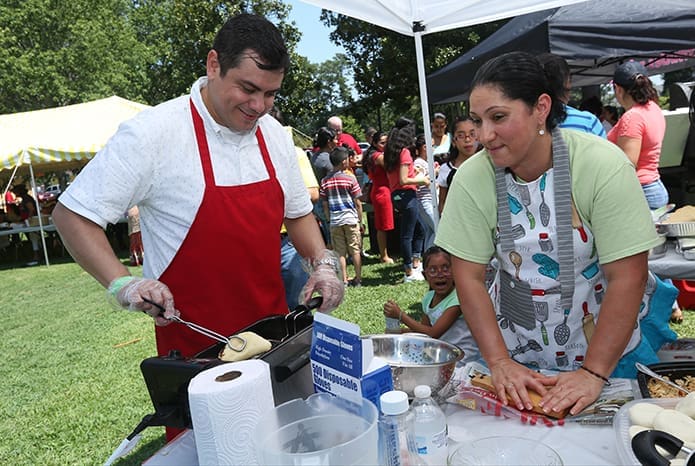 Newly ordained Father Gerardo Ceballos makes empanadas under the South American tent with Martha Garcia, a native of Colombia. Photo By Michael Alexander