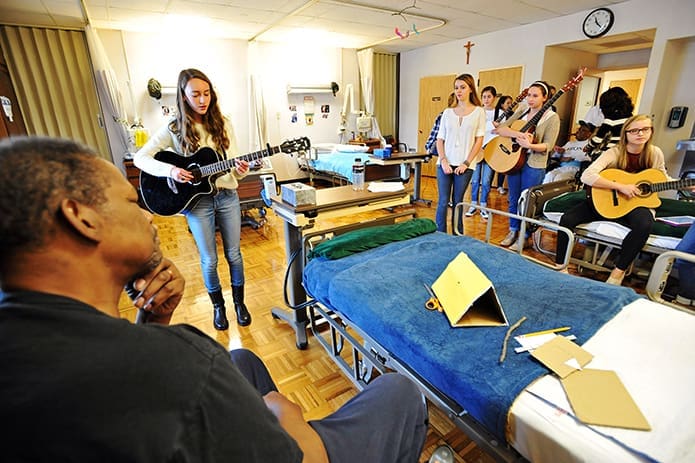 Mary Margaret Cozart, 14, left center, a student at St. Pius X High School, performs a song for patient George Harris, Jr., as other members of TROTT listen at Our Lady of Perpetual Help Home. Photo By Lee Depkin