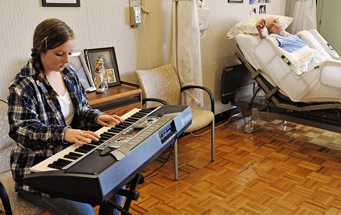 St. Pius X High School student Sam Repasky, left, plays the keyboard for patient Fionnuala Nichols.
