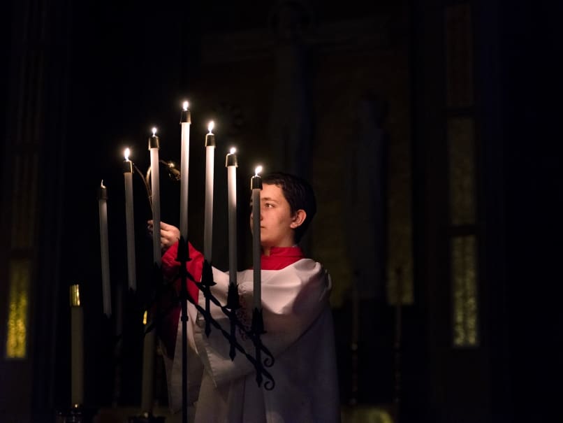 An altar server lights the candles during a Tenebrae service at Cathedral of Christ of the King. Tenebrae is a solemn prayer service of song and Scripture, marked by the gradual extinguishing of lights until the service ends in darkness and silence. Photo by Johnathon Kelso