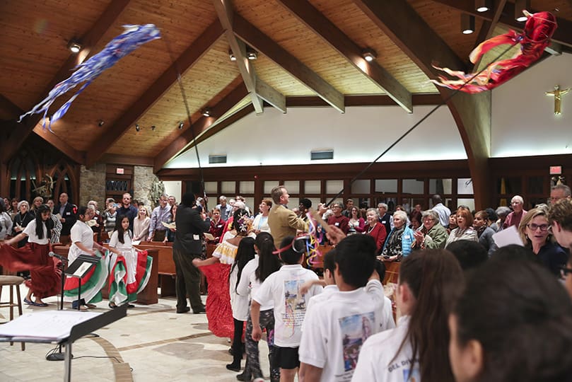 Children follow adults waving streamers over the congregation, as they lead the opening procession into and around the sanctuary during the gathering hymn. Photo By Michael Alexander
