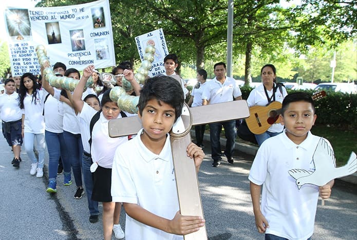 Jesus Solorio, 11, of St. Thomas Aquinas Church, Alpharetta, carries the cross, which is part of a large, crafted rosary held up by other children following behind him. They were part of the opening procession. Photo By Michael Alexander