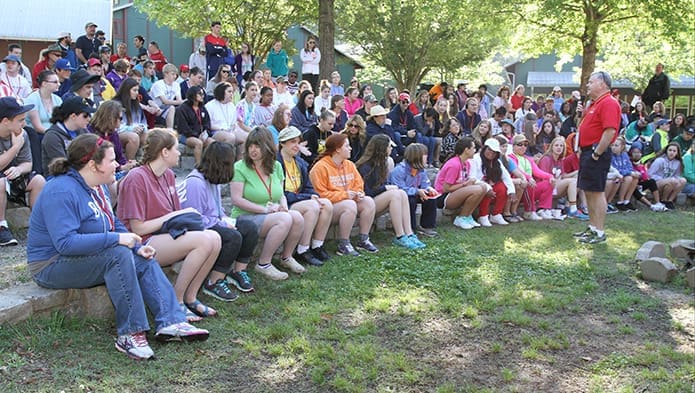 Deacon Bob Brunton of St. Thomas Aquinas Church, Alpharetta, standing right, leads a period of prayer and reflection in the amphitheater before morning activities begin at Toniâs Camp, May 2. Brunton has been a long time volunteer at the annual weekend camp for young men and women with developmental disabilities. Photo By Michael Alexander