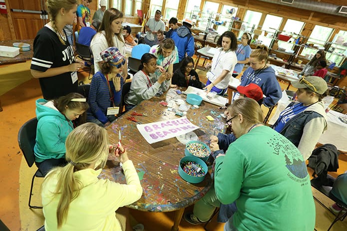 Campers and volunteers participate in an arts and crafts project. This particular table of campers worked on bracelet beading. Photo By Michael Alexander