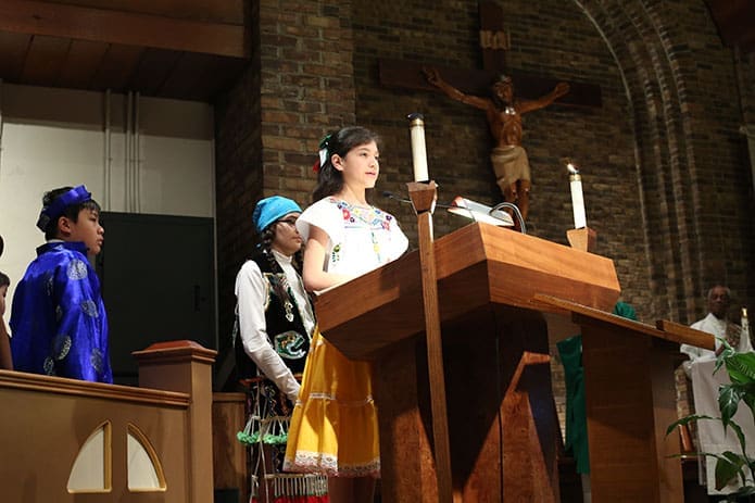 St. John the Evangelist fifth-grader Kathy Calderon was one of several students who participated in the prayers of the faithful, appearing in traditional dress and praying in their native language. Photo By Michael Alexander