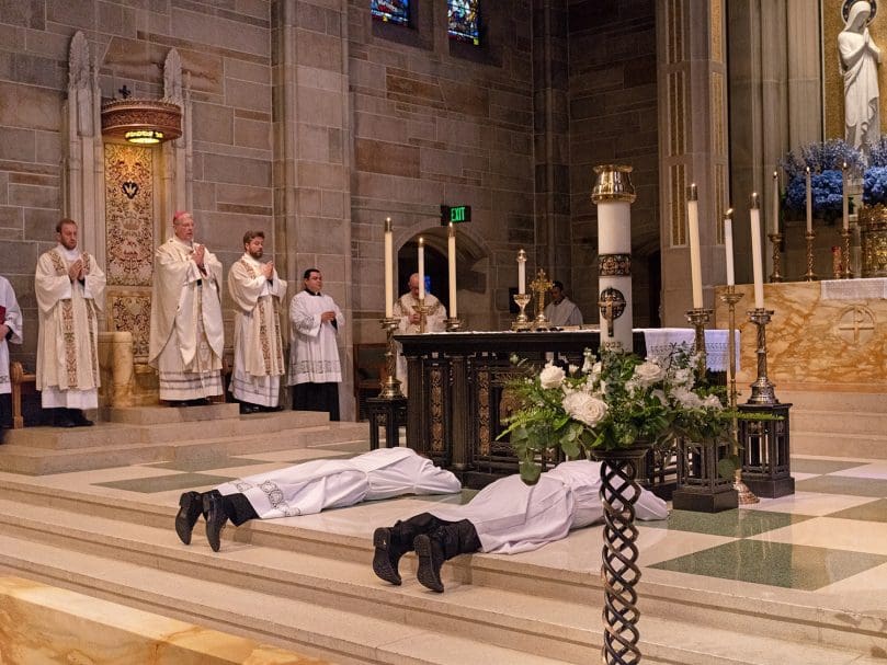 Evan Glowzinski and Matthew Howard lie prostrate at the altar during the Litany of Supplication at their ordination as deacons. They will serve for one year at parishes in preparation for the priesthood. Photo by Johnathon Kelso