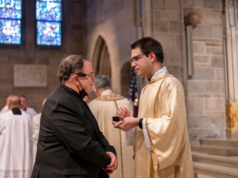 Deacon Pete Coppola administers holy Communion to his father during the ordination to the transitional diaconate. Photo by Johnathon Kelso
