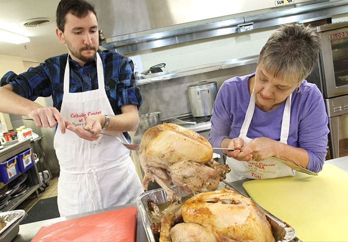 Jesse Nunez, left, and Sue Brassard lift one of the succulent turkeys out of the pan onto a platter so they can be sliced up for the upcoming dinner. The food preparation team cooked a total of six turkeys Nov. 22. Photo By Michael Alexander