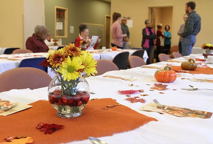 A few residents of the Jesse B. Denney Tower, Athens, sit at the tables, festively decorated and set for the Nov. 22 Thanksgiving dinner. In the background volunteer members of the serving crew gather as they await the foodâs arrival from the University of Georgia Catholic Center. This year marked the 20th annual dinner at the residential building for seniors. Photo By Michael Alexander
