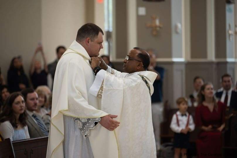 Father Sunny Punnakuziyil, right, puts the finishing touches on newly ordained Father Sean Lee’s vestments during the Mass of ordination to the priesthood at Holy Vietnamese Martyrs May 30. Father Lee said it only made sense for his pastor to serve as his vesting priest, as he helped ‘clothe’ his understanding of the priesthood.