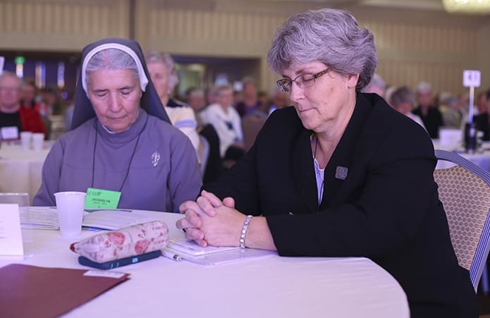 Marian Sisters of the Diocese of Lincoln, Nebraska, Jacquelyn Darner, left, and Sisters of Sts. Cyril and Methodius Deborah Borneman shut their eyes with others as they contemplate the future identity of the conference for women religious. Photo By Michael Alexander