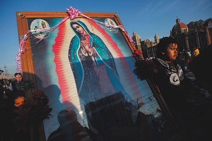 A pilgrim carries an image of Our Lady of Guadalupe during celebrations marking her feast day, Dec. 12, 2012, outside the Basilica of Our Lady of Guadalupe in Mexico City. Mary is associated with everything from national identity in Mexico to the mother earth in Chile to the national patroness of many of the countries in between.