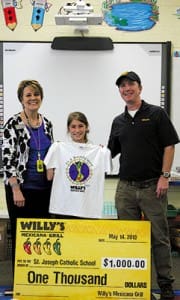 McKinley Roth, center, holds her prize-winning T-shirt which brought a $1,000 donation to her school and a month of free burritos for McKinley. She is congratulated by Patricia Allen, left, her principal at St. Joseph School, Marietta, and Willy Bitter of Willy’s Mexicana Grill.