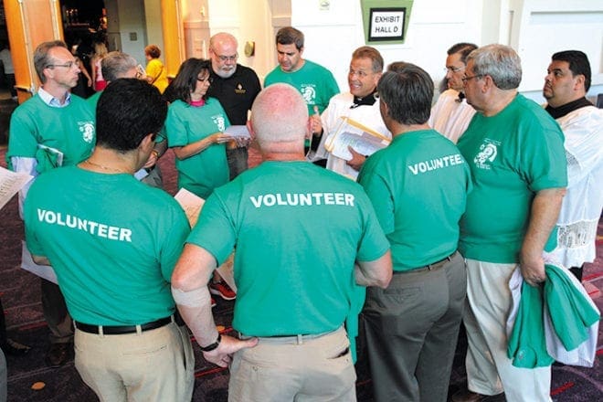 Deacon Gary Schantz of St. Andrew Church, Roswell, right center, holding envelope and paper, conducts a meeting with volunteers before the opening Mass of the 18th annual Eucharistic Congress at the Georgia International Convention Center, College Park.