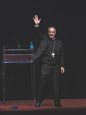 Bishop Luis R. Zarama lifts his hand to the applause from the Spanish track crowd.