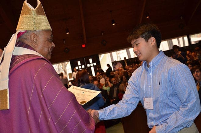 Archbishop Wilton D. Gregory congratulates Eric Lee, of Korean Martyrs Catholic Church in Doraville, chosen the outstanding youth from his parish. Fifty-four teens were honored.