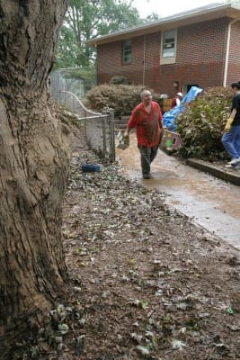Surrounded by a mud soaked landscape left by the Sept. 21, 2009 flash flood, Msgr. David Talley, pastor of St. John Neumann Church, Lilburn, walks down a path to a dumpster as he and others remove trash and debris from the parish preschool.