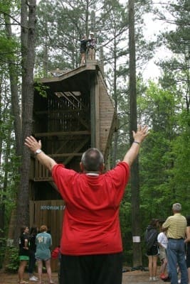 From ground level Monsignor David Talley, chaplain for the Disabilities Ministry, verbally encourages a camper preparing to ride the zip line from its 40-foot platform starting point. For 44 years the Archdiocese of Atlanta has embraced and supported Catholics with disabilities through its weekend camp ministry. 