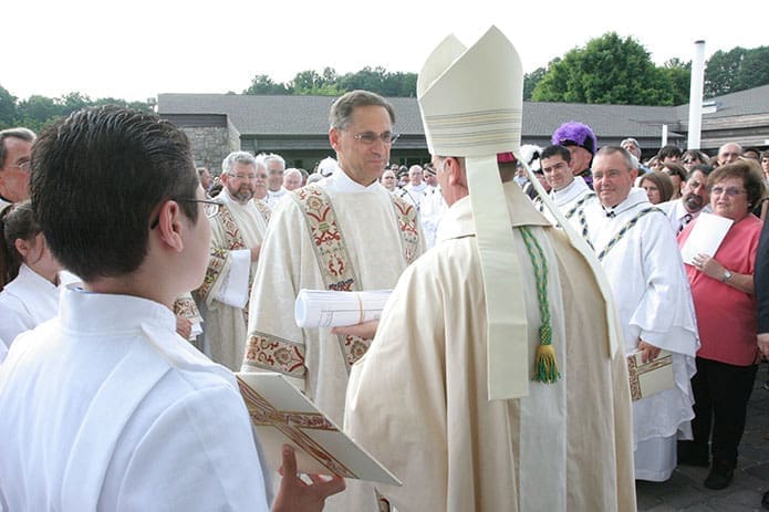 Deacon Terry Bigelow, facing camera center, presents the church plans to Bishop Luis Zarama at the entrance to the new St. John Neumann Church, Lilburn, in 2010. David Talley, the pastor of St. John Neumann Church at the time, is standing in the background, right.
