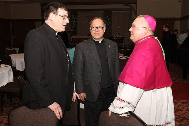 During a reception following the solemn vespers, Bishop-designate David Talley chats with two classmates from St. Meinrad Seminary, St. Meinrad, Ind., Father Thomas Schliessmann of the Archdiocese of Indianapolis, left, and Father Gregory Spencer of the Diocese of Raleigh. 